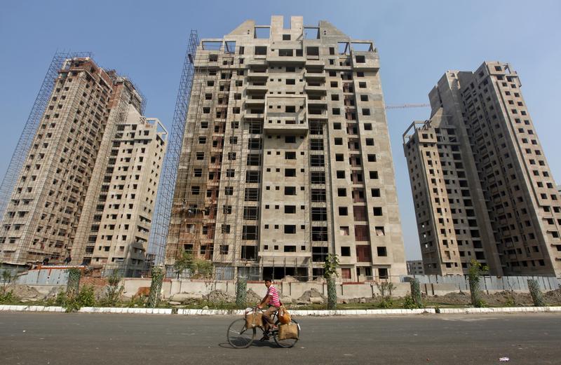 Man cycles past residential buildings under construction in Kolkata
